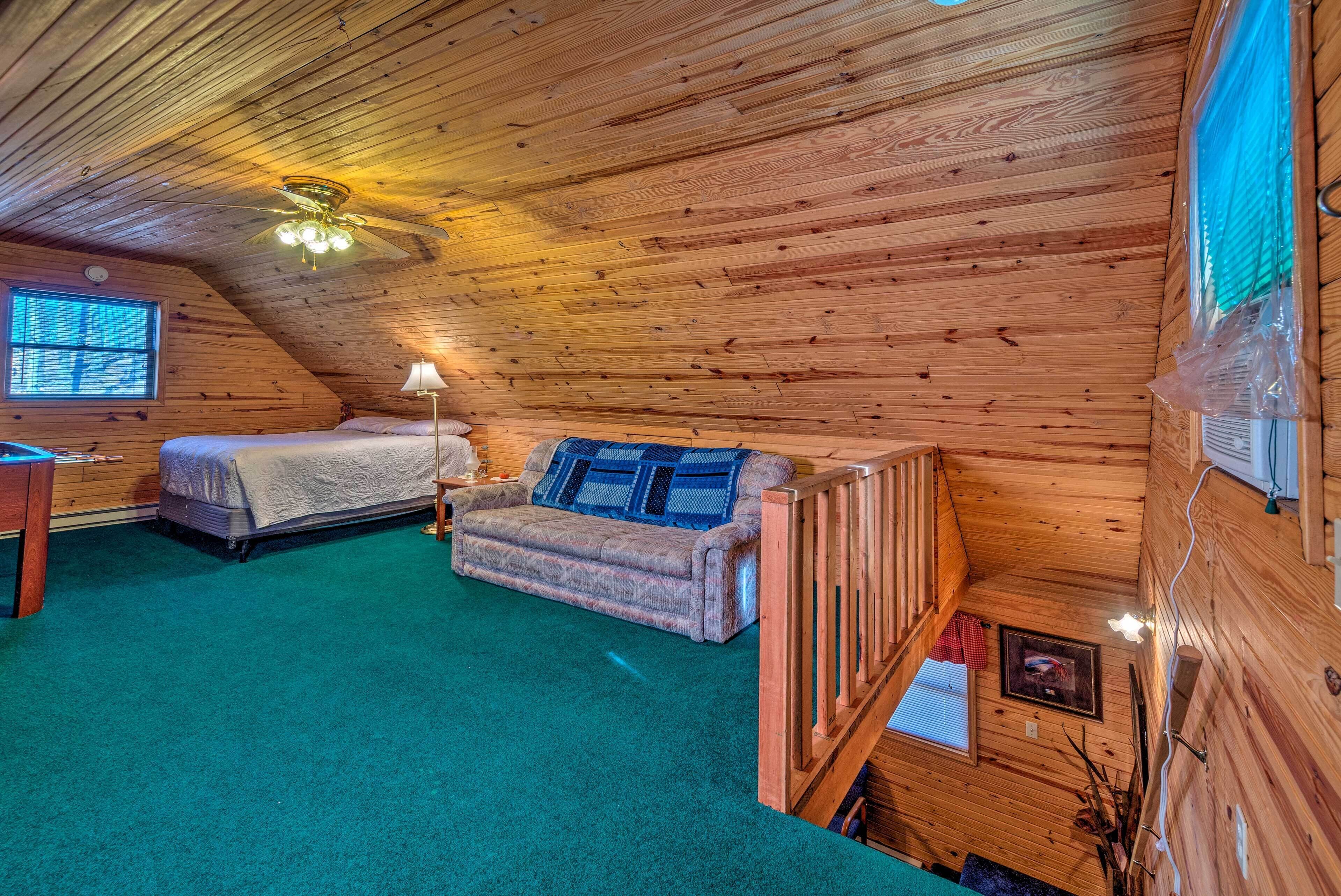 A cozy cabin with a wooden interior, a bed, a sofa, and a ceiling fan.