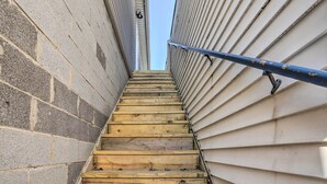 Eine Holztreppe führt zu einem Gebäude mit weißer Fassade.