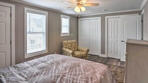 Ein Schlafzimmer mit Bett, Stuhl, Deckenventilator und zwei Türen.