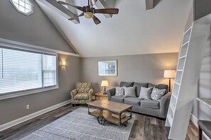 A living room with a gray couch, patterned armchair, and a coffee table with wheels. - Updated Lake Erie Home ~ 34 Mi to Cedar Point! (Lorain)