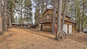 A rustic wooden building with a balcony, surrounded by tall pine trees. - Rustic Western Home: Walk to Winchester Lake! (Winchester)