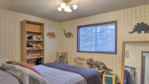 A child's bedroom with a bed, a wooden toy shelf, dinosaur wall decorations, a window, and a mirror. - Rustic Western Home: Walk to Winchester Lake! (Winchester)