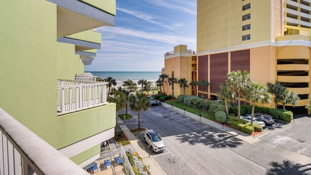 A multi-story hotel with a parking area, palm trees, and a view of the beach. - Myrtle Beach Condo w/ Lazy River: Walk to Beach! (Myrtle Beach)