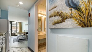 A hallway with a kitchen area, a dining table, and a bathroom with a sink and mirror. - Myrtle Beach Condo w/ Lazy River: Walk to Beach! (Myrtle Beach)