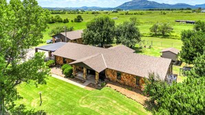 A large house with a stone exterior and a tiled roof, surrounded by a well-maintained lawn and trees. - Spacious Country Home Near Ft Sill & Medicine Park (Lawton)