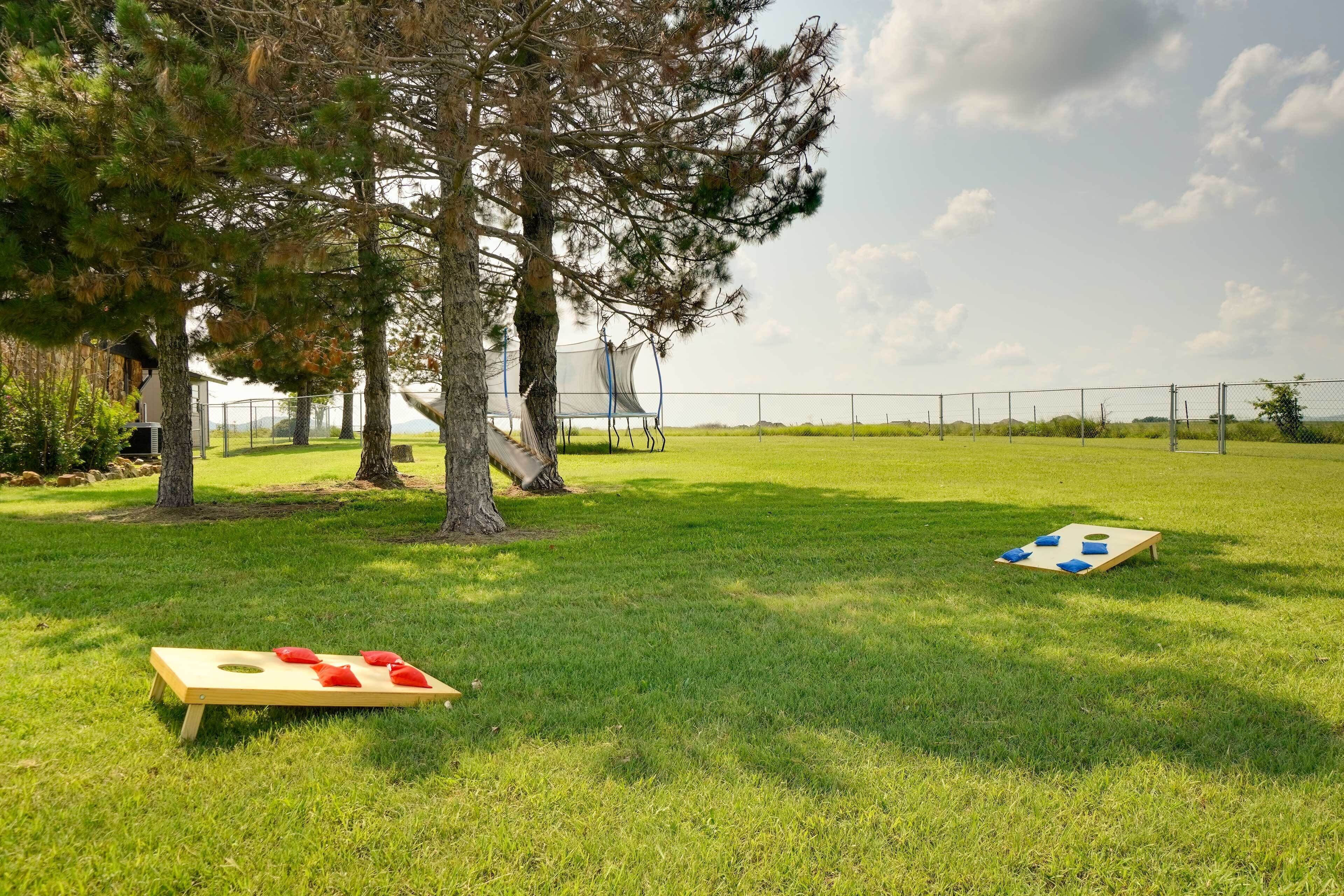 A grassy outdoor area with two wooden boards for a game, surrounded by trees and a fence.