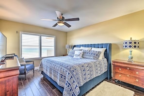 A bedroom with a bed, a desk, a chair, a dresser, a lamp, and a ceiling fan. - Luxe Oceanfront Condo w/ Pool, Beach Access + Gear (Ormond Beach)