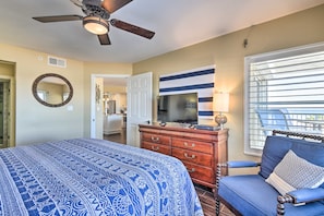 A bedroom with a bed, a dresser, a television, a chair, and a window with blinds. - Luxe Oceanfront Condo w/ Pool, Beach Access + Gear (Ormond Beach)