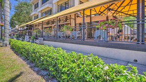 Ein Hotel mit Außenbestuhlung, einer überdachten Terrasse und einem gepflegten Garten.