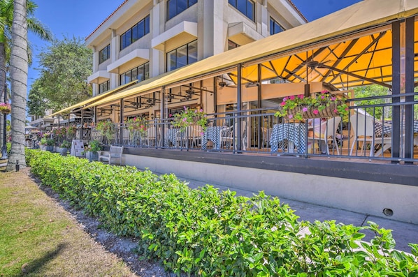 Um hotel com área externa para sentar, um alpendre coberto e um jardim bem cuidado.