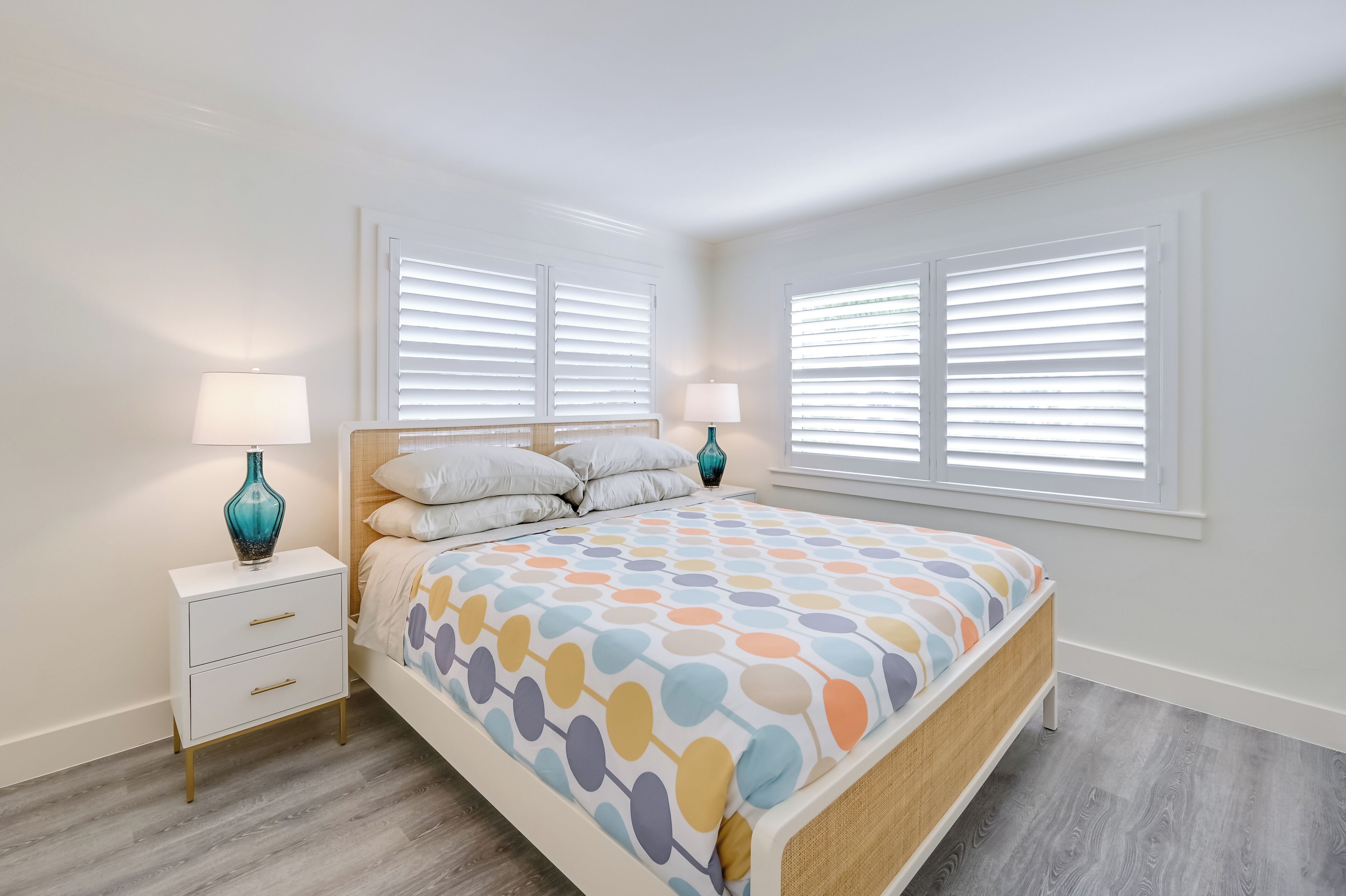 Een slaapkamer met een bed, twee nachtkastjes en een raam met zonwering.