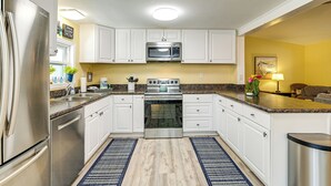 Een moderne keuken met witte kasten, roestvrijstalen apparatuur en een granieten aanrecht.