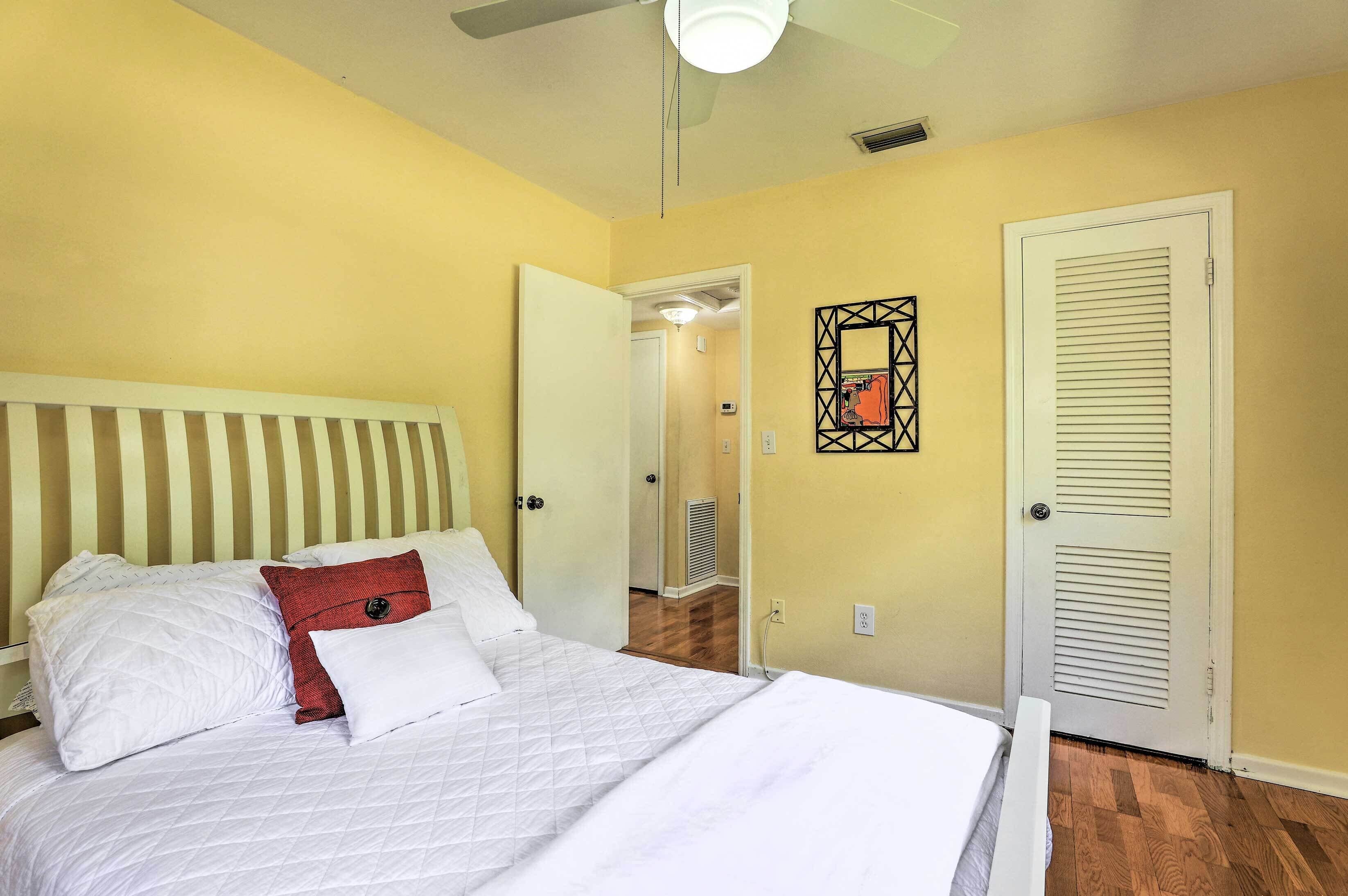 A bedroom with a bed, a ceiling fan, and a door.