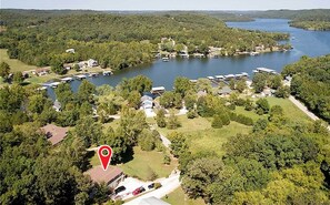 An aerial view of a lakeside resort with multiple cabins and a central building, surrounded by dense forest.