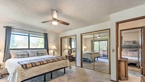 A bedroom with a bed, bedside lamps, a ceiling fan, and a large mirror. - Deck & Hot Tub: Rustic Groveland Home! (Groveland)