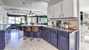 Une cuisine moderne avec des meubles de couleur bleu foncé, un plan de travail en marbre et un îlot central doté de tabourets de bar.