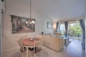 A dining area with a round table and chairs, a sofa, a balcony with a view, and a painting on the wall. - Snowbird's Escape: 6 Mi to the Beach & Old Naples! (Naples)