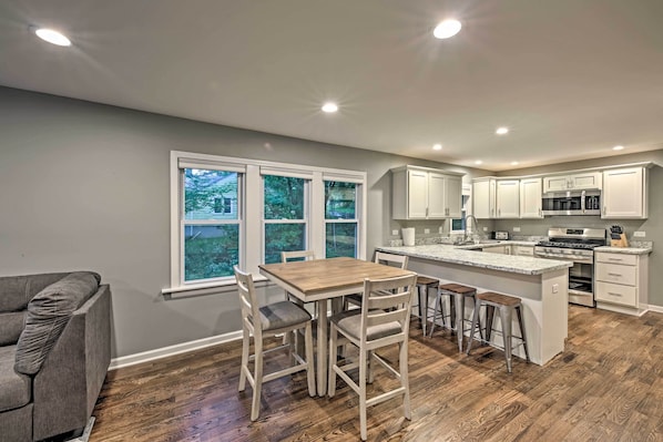 A modern kitchen with white cabinets, a wooden dining table, and a large window. - Updated Twin Lakes Cottage, Walk to Lake Mary (Twin Lakes)