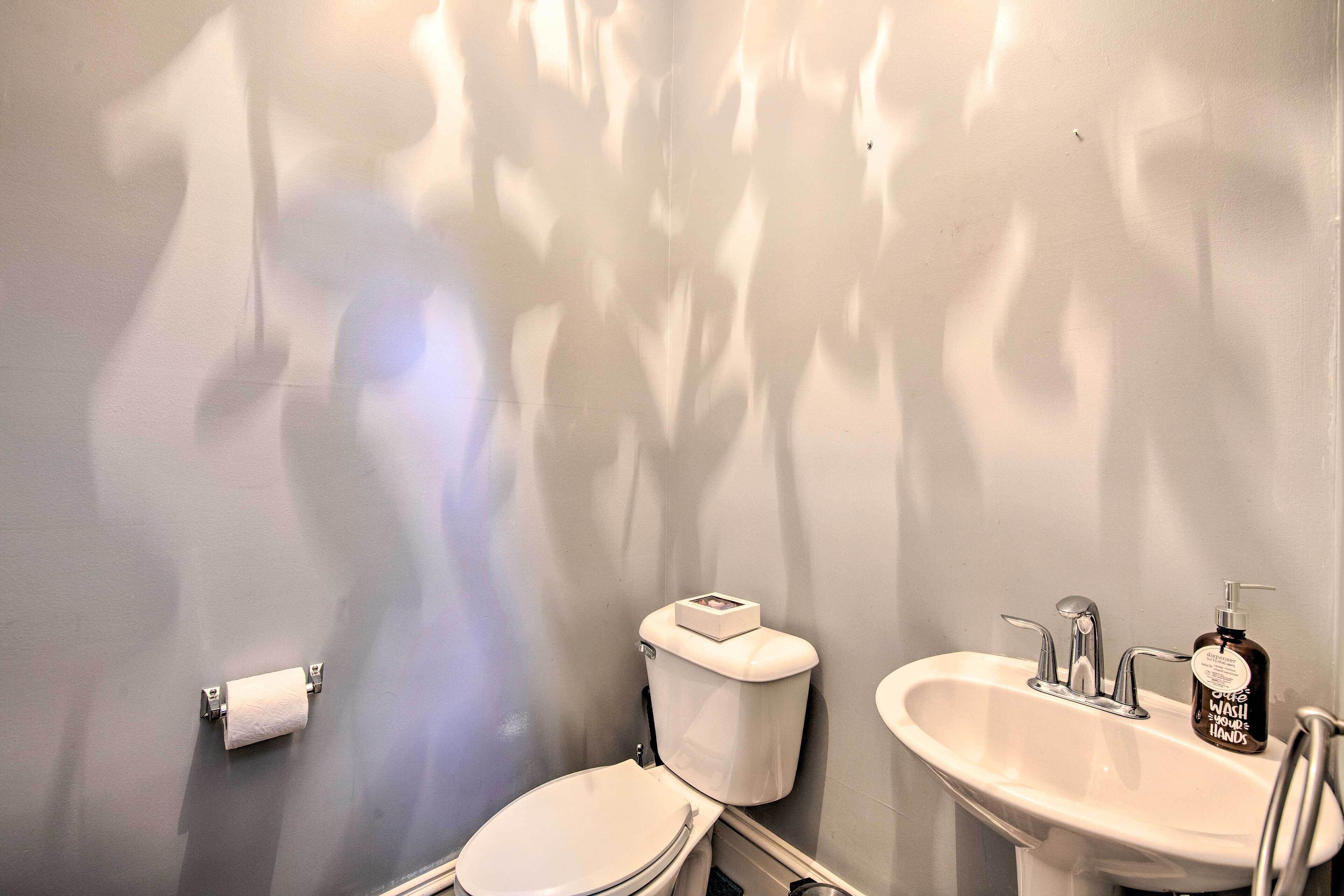 A bathroom with a toilet, sink, and a bottle of hand soap.