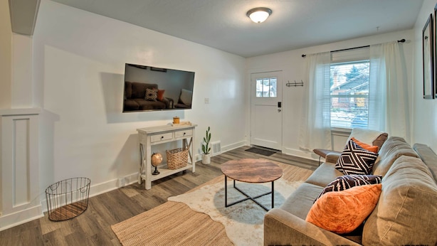 A living room with a flat-screen TV mounted on the wall, a sofa with patterned cushions, a coffee table, and a small side table with decorative items. - Modernized SLC Duplex w/ Yard ~ 4 Mi to Dtwn! (Salt Lake City)