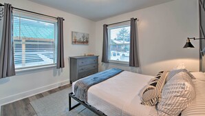 A bedroom with a bed, a dresser, and two windows with curtains. - Modernized SLC Duplex w/ Yard ~ 4 Mi to Dtwn! (Salt Lake City)