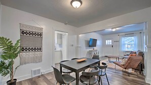 A modern living room with a dining area, a large plant, and a TV on the wall. - Modernized SLC Duplex w/ Yard ~ 4 Mi to Dtwn! (Salt Lake City)