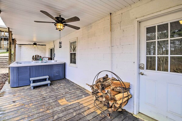 A covered outdoor deck with a hot tub, wooden steps, and a stack of firewood. - Beckley Studio w/ Hot Tub, 4 Mi to WVU Tech! (Beckley)
