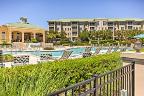 A hotel with a pool area, lounge chairs, and a well-maintained garden.