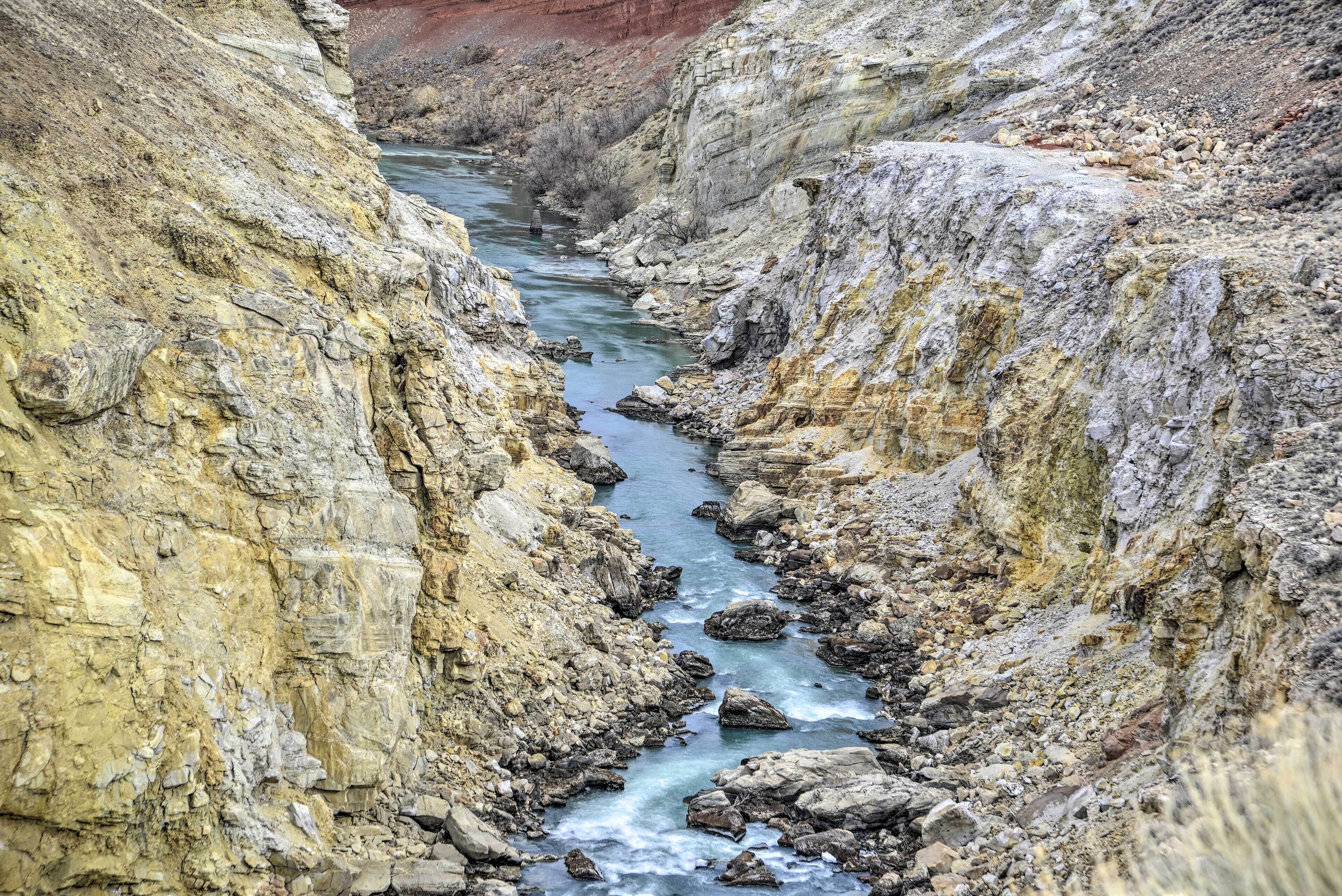 A narrow canyon with a river flowing through it.