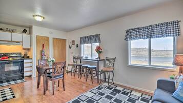 A cozy kitchen with a stove, cabinets, and a dining area with chairs and a table.