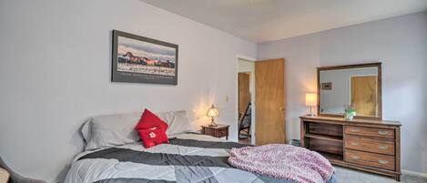 Un dormitorio con cama, cómoda, espejo, mesita de noche y un cuadro en la pared.