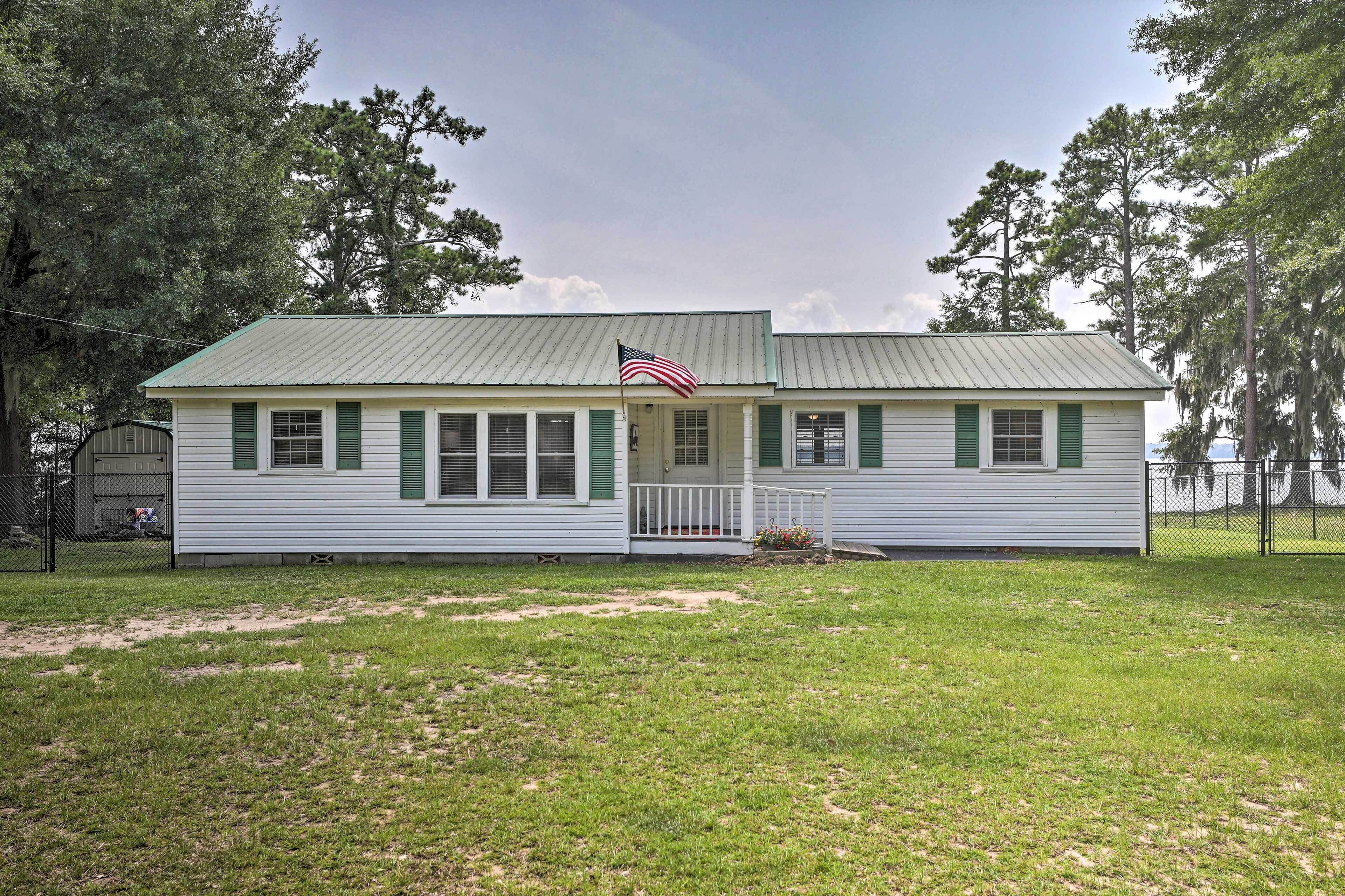 A single-story house with a green roof, white siding, and green shutters.