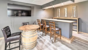 Une cuisine moderne avec un coin bar, des chaises en bois et un grand téléviseur à écran plat fixé au mur.
