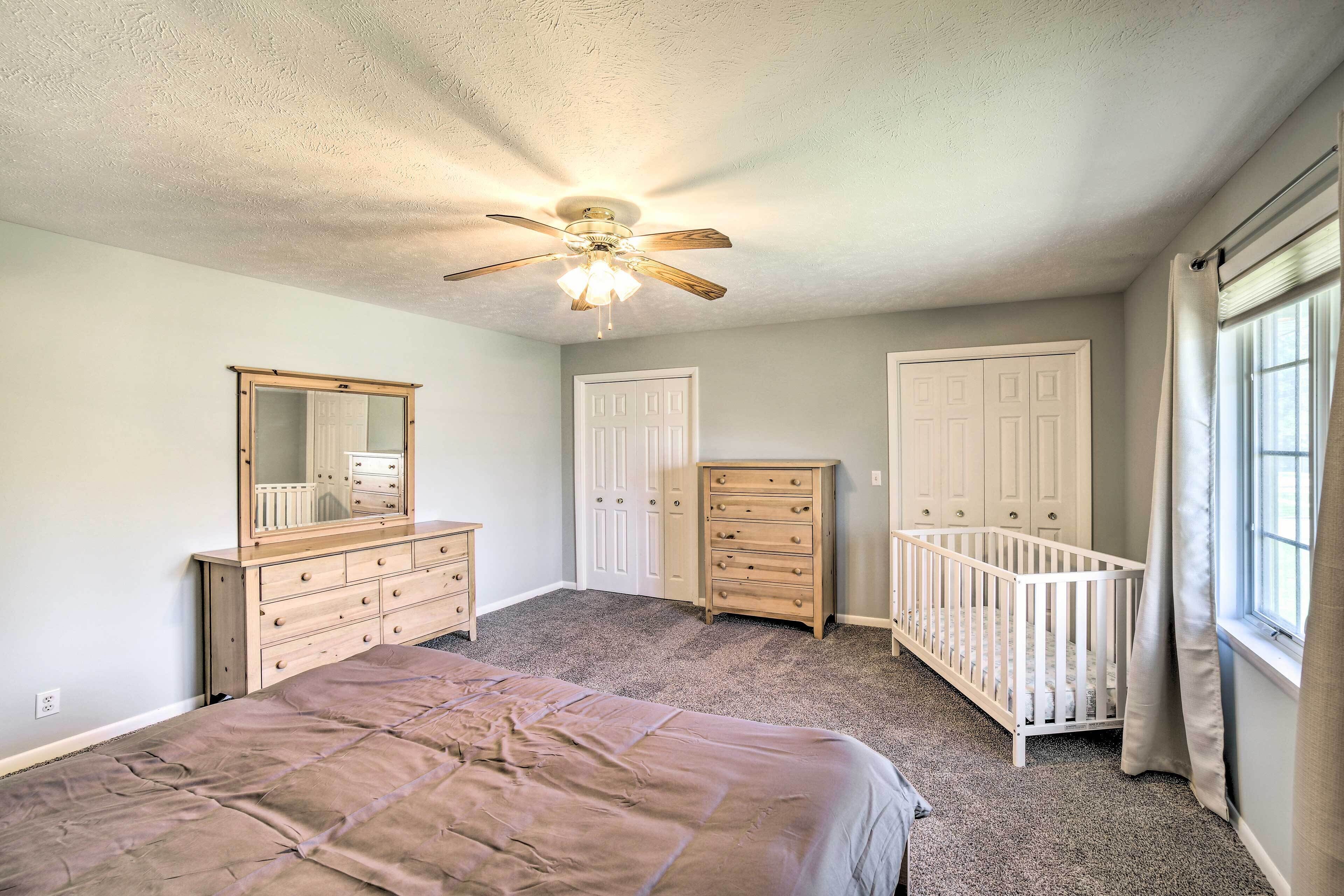 A bedroom with a bed, dresser, and a crib.