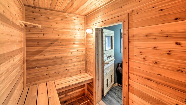 Un sauna en bois, doté de bancs et d’une porte donnant sur une autre pièce.