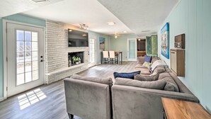 Un salon spacieux avec une cheminée en pierre, un grand canapé et un coin repas comprenant une table et des chaises.