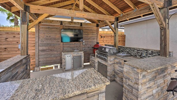 Een buitenkeuken met een stenen werkblad, een ingebouwde grill en een houten wand.