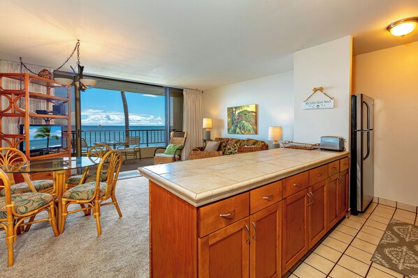 A kitchen with a large island, wooden cabinets, and a view of the ocean.