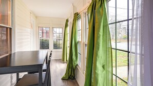 Een kamer met een groot raam, een eettafel en stoelen.