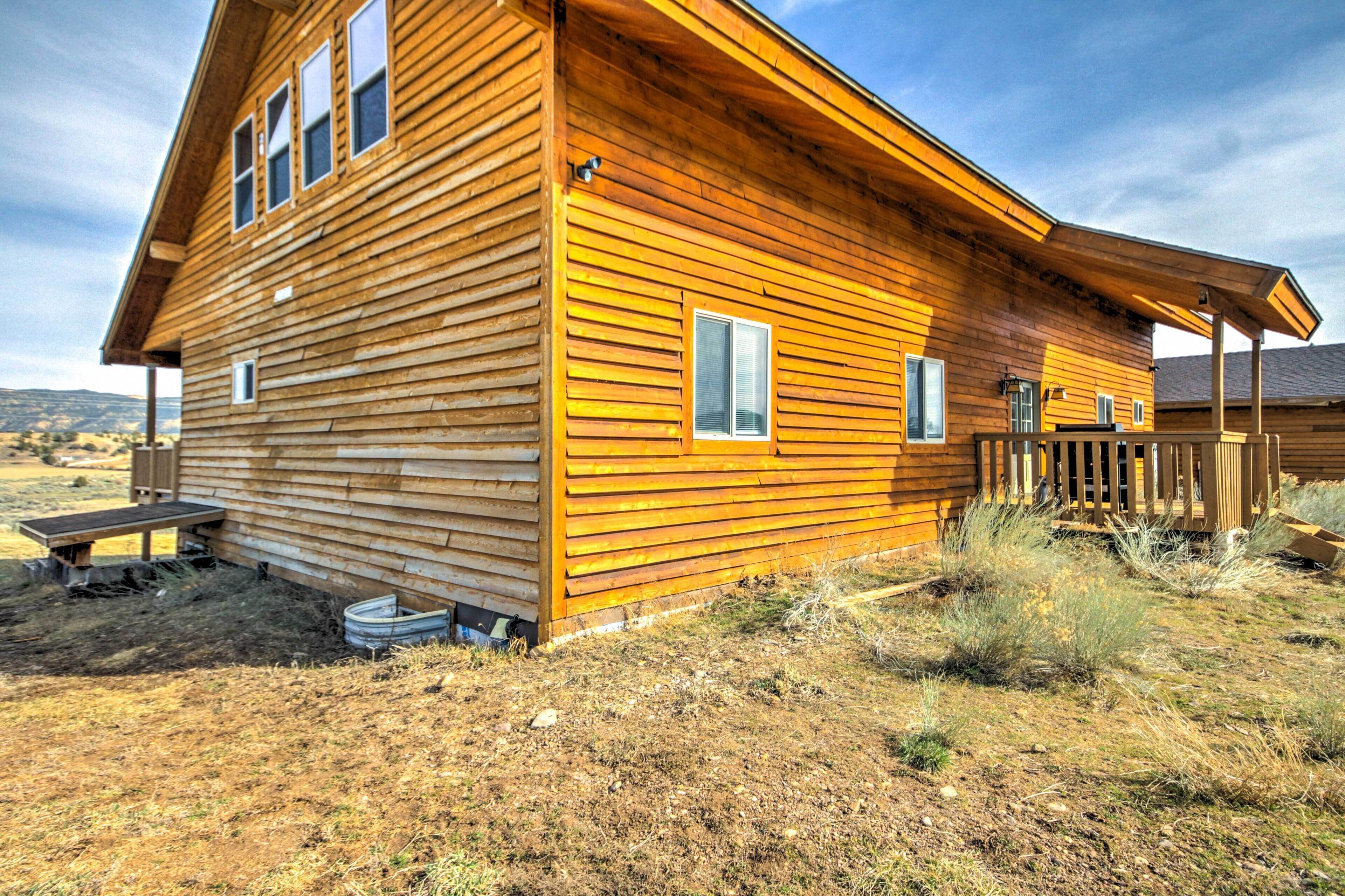 Een houten chalet met een veranda, een kleine aangeboude schuur, en een heldere lucht.
