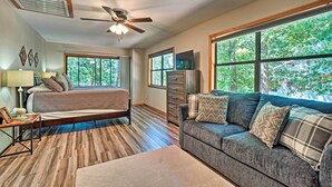 A bedroom with a bed, a dresser, a television, and a large window with a view of trees. - Home w/ Large Deck on Table Rock Lake! (Golden)
