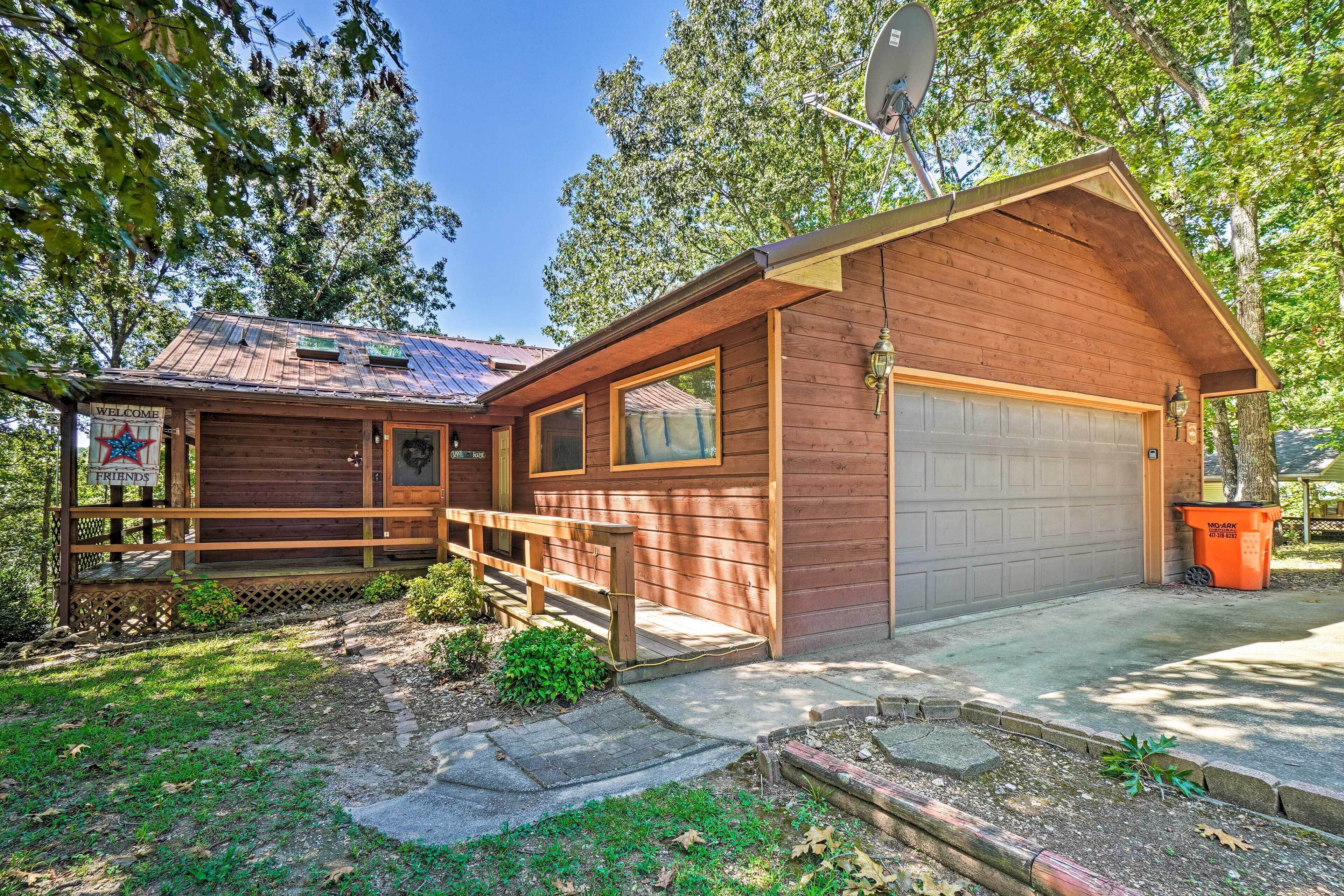 Een houten chalet met garage, veranda en een schotelantenne.