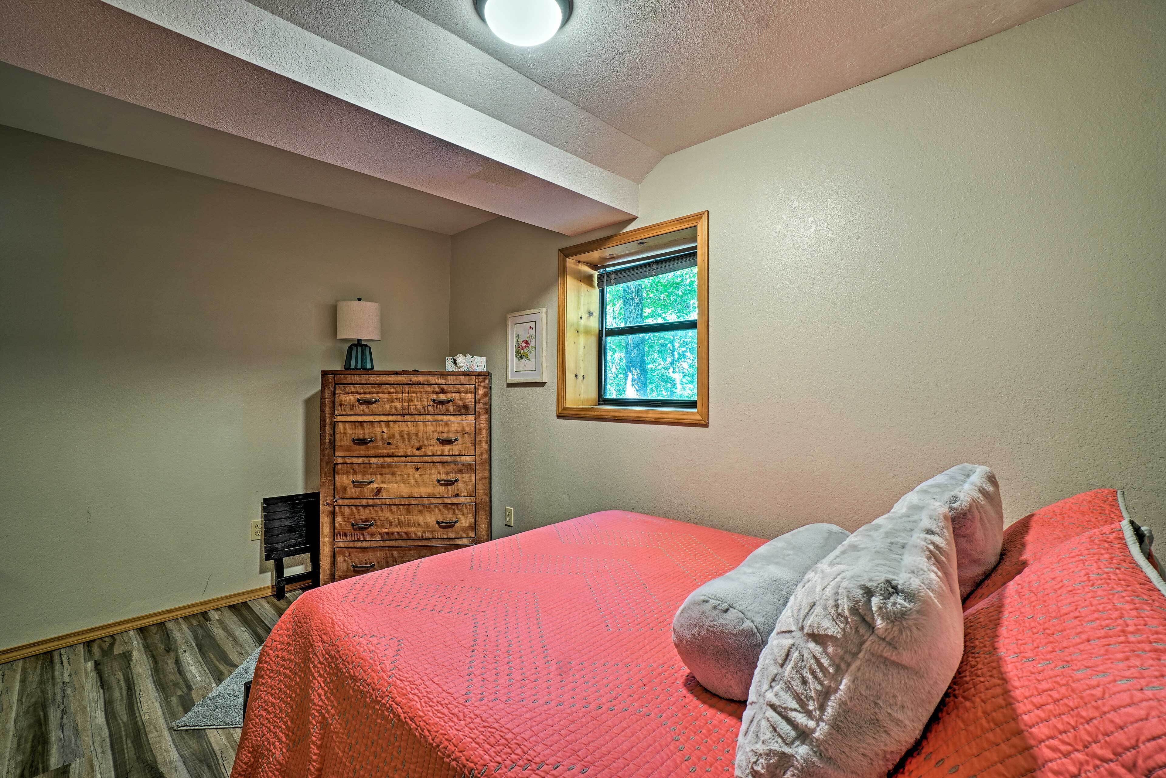 A bedroom with a bed, a dresser, a window, and a lamp.