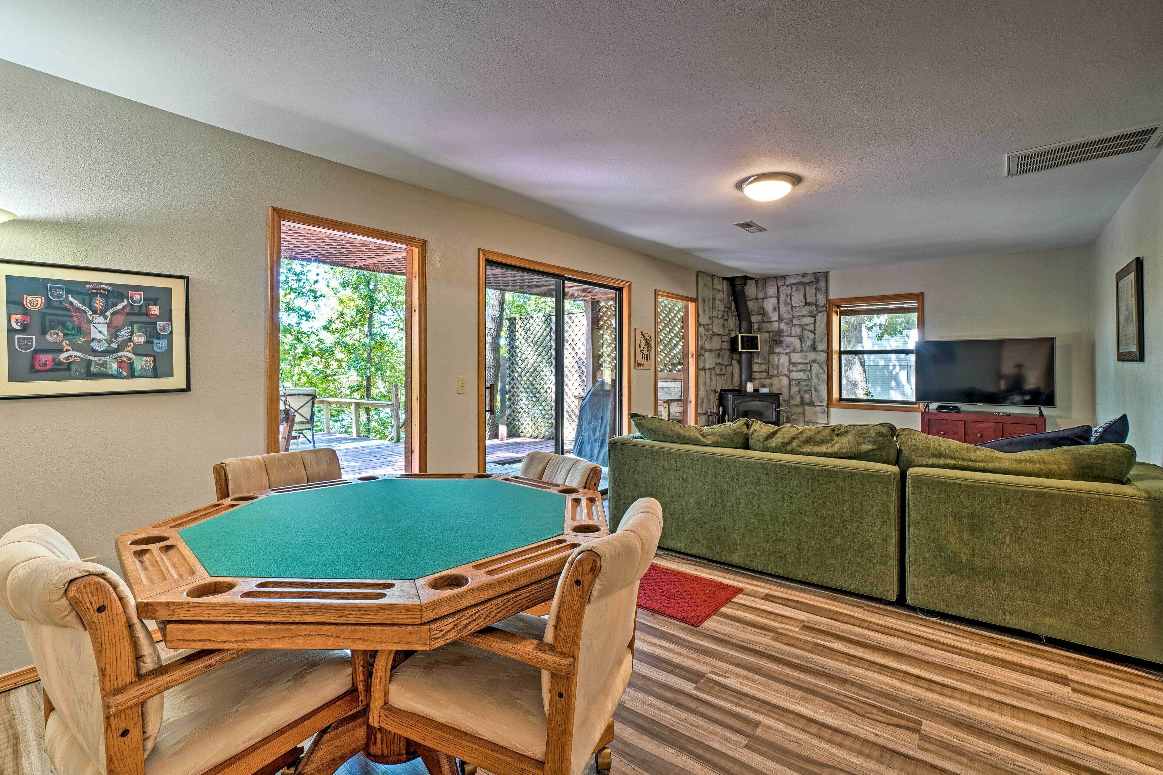 A pool table in a room with a green couch and a stone fireplace.