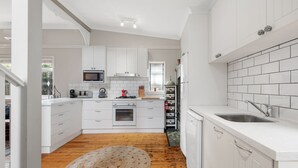 Une cuisine moderne avec des meubles blancs, un four à micro-ondes, une cuisinière et un évier.