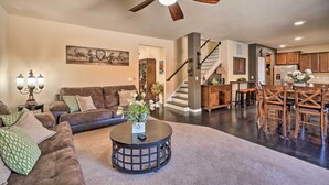 A spacious living room with a dark wood coffee table, a brown leather sofa, and a ceiling fan. - Pet-friendly Parker House Rental w/ Home Gym! (Parker)