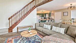 Un salon avec un escalier en bois, un canapé, une table basse et un tapis à motifs.