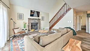 Un salon avec une cheminée, un canapé, une table basse et un escalier.