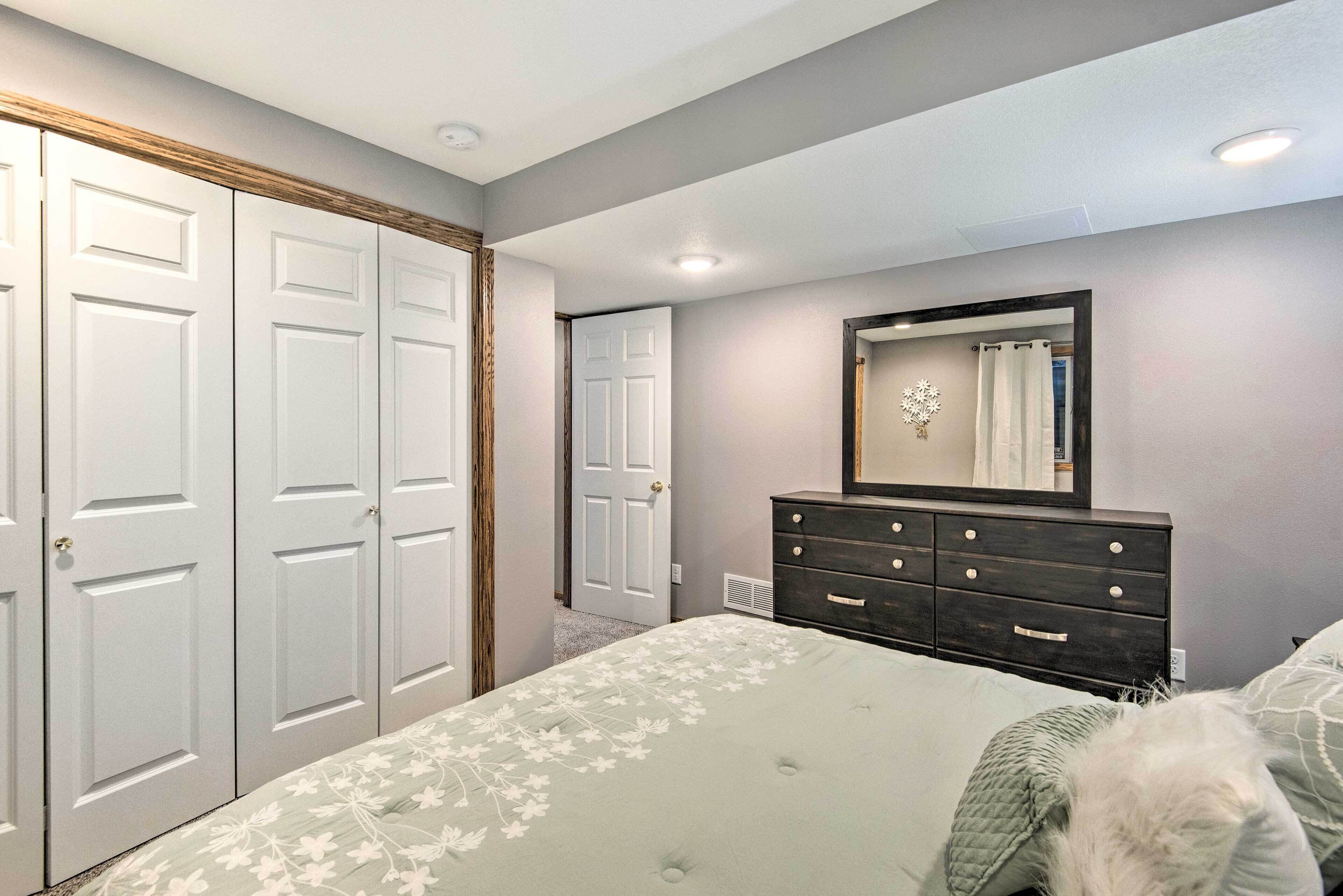 Un dormitorio con cama, cómoda y dos puertas.