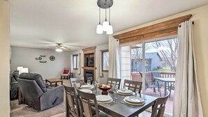 Un coin repas avec une table dressée pour quatre personnes, une cheminée et une vue sur l’extérieur.